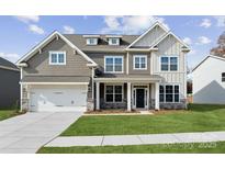 Two-story house with gray siding, stone accents, and a three-car garage at 223 E Warfield Dr, Mooresville, NC 28115