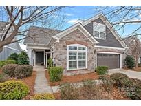 Beautiful home featuring a stone facade, gray siding, manicured landscaping, and attached two car garage at 16115 Lakeside Loop Ln, Cornelius, NC 28031