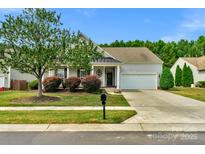 Charming one-story house with a metal roof, landscaping, and a two-car garage at 2024 Holly Villa Cir, Indian Trail, NC 28079