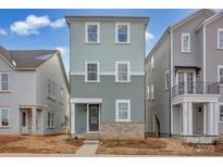 Three-story townhome with light green siding and brick accents at 207 Davidson Gateway Dr, Davidson, NC 28036