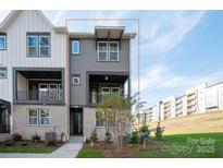 Charming townhome boasts a modern gray exterior with brick accents and a cozy second-story balcony at 440 Nathaniel Way # Brx0041, Charlotte, NC 28213