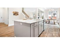 Modern kitchen island with marble countertop, stainless steel sink and faucet, gray cabinets, and adjacent dining area at 332 Shinnville Rd, Mooresville, NC 28115