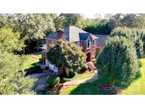 Stunning red brick two-story home with mature trees, lush landscaping, and a welcoming front entrance at 102 Sleaford Ct, Dallas, NC 28034