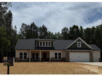 Charming single-Gathering home featuring a two-car garage, stone accents, and a well-manicured lawn at 1025 Baylor Grv, Monroe, NC 28112