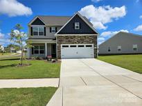 Two-story house with stone and siding, two-car garage, and landscaped lawn at 179 Wembury Ln, Troutman, NC 28166