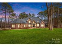 Stunning brick home featuring a well-manicured lawn and lush landscaping, offering timeless elegance and curb appeal at 130 Stonewall Beach Ln, Mooresville, NC 28117