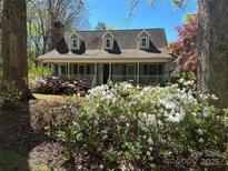 Charming home with dormers and a cozy front porch, surrounded by colorful azaleas and mature landscaping at 1409 Trinity Church Rd, Monroe, NC 28112