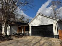 Newly renovated home with a white exterior, black garage door, and landscaping at 3305 Cameo Trl, Gastonia, NC 28056