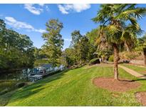 Picturesque lake view with a private dock, lush landscaping, and mature trees for a serene outdoor setting at 4145 Cindy Ln, Denver, NC 28037
