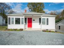 Charming white house with red door, gray gravel driveway, and well-maintained landscaping at 83 Woodsdale Se Pl, Concord, NC 28025