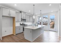 Well-lit kitchen features island with sink, stainless appliances, gray cabinets and modern pendant lighting at 1617 Blanche St, Charlotte, NC 28262
