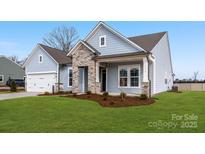 Charming single-Gathering home with stone accents, a well-manicured lawn, and a two-car garage at 3228 Gavin Ln, Harrisburg, NC 28075