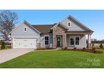 Charming single-story home featuring stone accents, a two-car garage, and a well-manicured lawn at 3228 Gavin Ln, Harrisburg, NC 28075