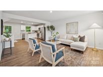 Bright living room with hardwood floors, neutral decor, and an open floor plan to the kitchen at 5008 Winding Jordan Ln, Charlotte, NC 28269