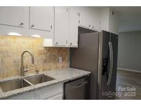 Well-lit kitchen featuring a stainless steel refrigerator, granite countertops, and tiled backsplash at 525 12Th Sw St # 26, Hickory, NC 28602