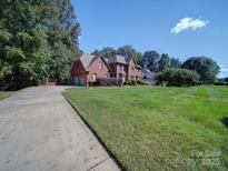 Spacious brick home featuring an attached two-car garage and a well manicured front lawn at 907 Weymouth Dr, Gastonia, NC 28056