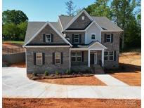 Stunning two-story brick home featuring a manicured lawn, complemented by dark shutters and a concrete driveway at 8605 Carly Ln, Mint Hill, NC 28227
