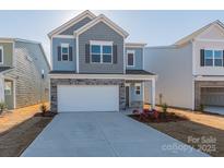 Charming two-story home with a two-car garage, stone accents, and blue siding at 1209 Red River Dr, Salisbury, NC 28144