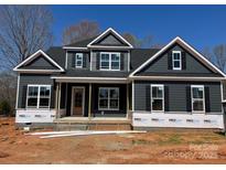New two-story home featuring dark siding, white trim, symmetrical windows, and a covered front porch at 552 Fern Hill Rd # 21, Mooresville, NC 28117
