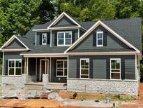 New construction home featuring gray siding, stone accents, black shutters, and a covered front porch at 552 Fern Hill Rd # 21, Mooresville, NC 28117