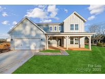 Two-story farmhouse features a front porch, attached two-car garage, and landscaped lawn at 7073 Stella Pl, Stanley, NC 28164