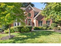 Charming two-story red brick home with manicured lawn and mature trees in a well-kept community at 15909 Woodcote Dr, Huntersville, NC 28078