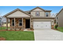 Charming two-story home featuring stone accents, a two-car garage, and a well-manicured lawn at 9916 Manor Vista Trl, Kannapolis, NC 28027