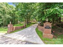 Long driveway leading to home with brick columns and manicured landscaping at 1134 Willow Oaks Trl, Matthews, NC 28104