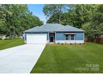 Charming blue one-story home with a manicured lawn, concrete driveway, and a two-car garage at 337 Autumn Dr, Harrisburg, NC 28075