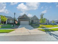 Charming single story home featuring a brick facade, well-manicured lawn and a two-car garage on a sunny day at 2014 Newstyle Way, Tega Cay, SC 29708