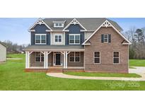 Inviting two-story home features a brick facade, covered porch, and manicured lawn at 123 Kepli Way, Mooresville, NC 28115