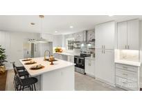 Modern kitchen with white cabinets, marble backsplash, and island at 5731 Brookhaven Rd, Charlotte, NC 28210