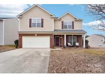 Two-story house with a beige exterior, brick accents, and a double-car garage at 7206 Sandown Ct, Harrisburg, NC 28075