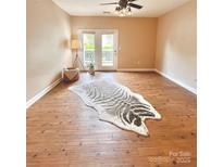Bright living room features wood floors, a ceiling fan, and a door leading to the outside at 11264 Hyde Pointe Ct, Charlotte, NC 28262