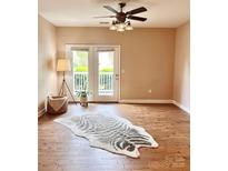 Bright living room with wood floors, ceiling fan, and double doors leading to a balcony at 11264 Hyde Pointe Ct, Charlotte, NC 28262