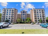 A condominium building with balconies and a parking lot under a sunny blue sky at 211 Heritage Blvd # 502, Fort Mill, SC 29715