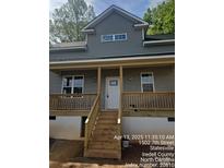 Charming home featuring a gray exterior, covered front porch, and a welcoming entrance with stairs and white door at 1506 7Th St, Statesville, NC 28677