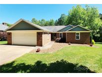 Charming single-story brick home featuring an attached two-car garage and a well-maintained front lawn at 2015 Pine Needle Ct, Gastonia, NC 28056
