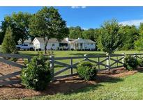 Charming single-story home with a long driveway, beautiful lawn, and decorative wooden fence at 796 Cornelius Rd, Mooresville, NC 28117