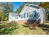 A light blue house is pictured with bright blue shutters with a well maintained lawn at 5039 Penn Rd, Iron Station, NC 28080