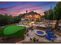 Expansive backyard featuring a putting green, hot tub, stone patio, and outdoor seating areas at 2723 Providence Pine Ln, Charlotte, NC 28270