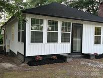 Charming house with a new black roof, white siding, and a beautiful touch of pink flowers in the front yard at 7608 Kershaw Camden Hwy, Kershaw, SC 29067