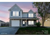 Charming two-story home showcasing stone accents, blue shutters, and a well-manicured lawn at 310 Foster Ln, Albemarle, NC 28001