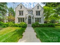 Stunning stone home with manicured lawn, mature trees, and a welcoming walkway leading to the front door at 1919 Kensal Ct, Charlotte, NC 28211