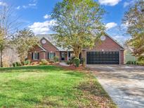 Charming brick home featuring mature landscaping, a black two-car garage, and a welcoming front entrance at 271 Lockhard Cir, Troutman, NC 28166