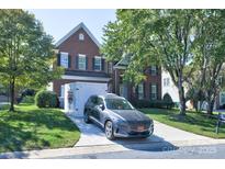 Charming two-story brick home with a well-manicured lawn, driveway, and modern grey SUV parked in front at 6416 Red Maple Dr, Charlotte, NC 28277