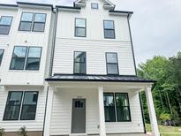 Modern farmhouse exterior with white siding, black trim, covered porch, and gray front door at 12126 Storm Ln # 53, Charlotte, NC 28277