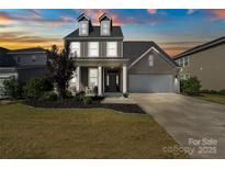 Charming two-story home with a manicured lawn and a two-car garage under a beautiful sunset at 535 Red Wolf Ln, Lake Wylie, SC 29710