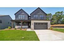 Two-story modern home with a gray exterior, stone accents, a two-car garage and manicured lawn at 15009 Brownleigh Ln # 26, Huntersville, NC 28078