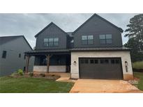 Modern two-story home with black siding, stone accents, and a covered front porch, creating a striking curb appeal at 15009 Brownleigh Ln # 26, Huntersville, NC 28078